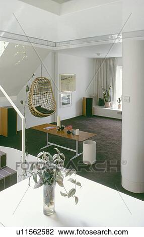 Open-plan white sixties living room with cane egg-chair suspended from ceiling View Large Photo Image Stock Image - Open-plan white sixties living room with cane egg-chair suspended from ceiling. Fotosearch