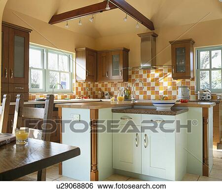 Stock Photograph - Orange and white wall tiles in terracotta kitchen with pastel blue fitted units. Fotosearch