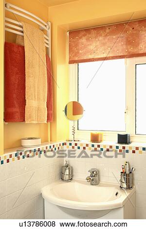 Orange blind on window above white basin in yellow family bathroom with red and yellow towels on wall-mounted radiator View Large Photo Image Stock Photo - Orange blind on window above white basin in yellow family bathroom with red and yellow towels on wall-mounted radiator. Fotosearch