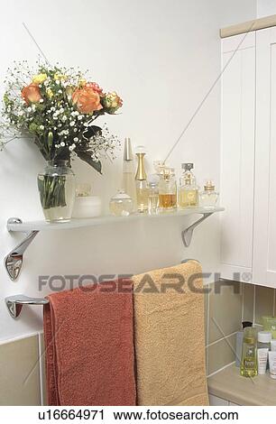 Orange roses and glass perfume bottles on glass shelf above orange towels in modern bathroom View Large Photo Image Stock Image - Orange roses and glass perfume bottles on glass shelf above orange towels in modern bathroom. Fotosearch