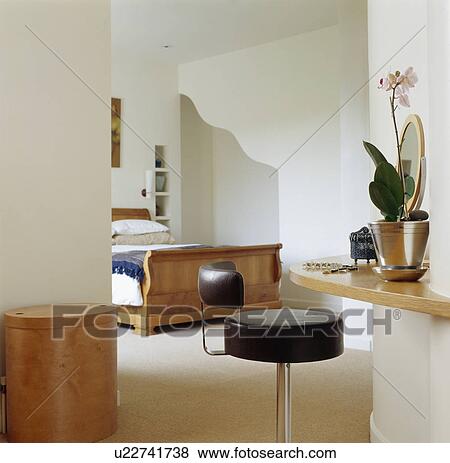 Stock Photo - Orchid in pot on shelf in modern white townhouse bedroom. Fotosearch