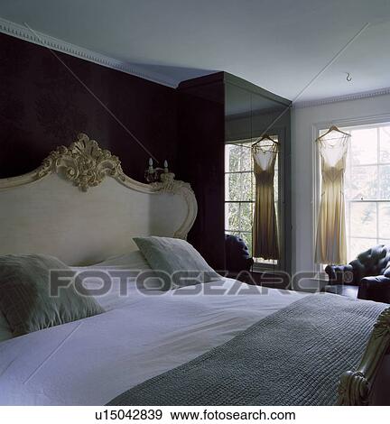 Ornate gilt-framed French bed with white bedlinen in country bedroom with mirrored wardrobe beside window View Large Photo Image Stock Photo - Ornate gilt-framed French bed with white bedlinen in country bedroom with mirrored wardrobe beside window. Fotosearch