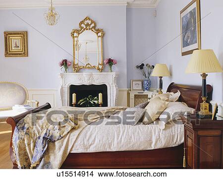 Ornate Gilt Mirror Above Fireplace In Pastel Blue Bedroom