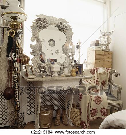 Ornate white mirror on cluttered table with marble top in white bedroom with jewellery draped on standard lamp View Large Photo Image Picture - Ornate white mirror on cluttered table with marble top in white bedroom with jewellery draped on standard lamp. Fotosearch