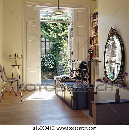 Oval antique mirror and metal framed chest in airy hall with double white doors open to small courtyard View Large Photo Image Stock Photo - Oval antique mirror and metal framed chest in airy hall with double white doors open to small courtyard. Fotosearch