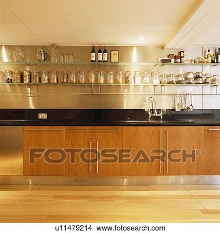 Picture - Pale wood cupboards in modern kitchen with stainless-steel shelving . Fotosearch