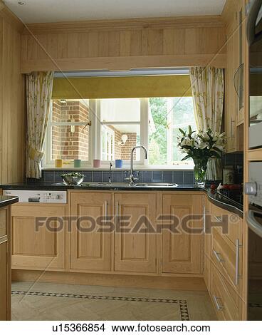 Picture - Pale wood fitted units in traditional country kitchen. Fotosearch