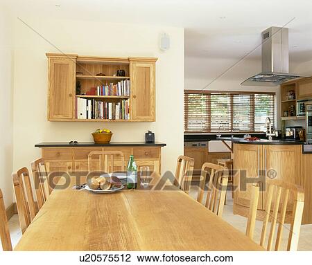 Stock Image - Pale wood table and chairs in large open-plan kitchen dining room. Fotosearch