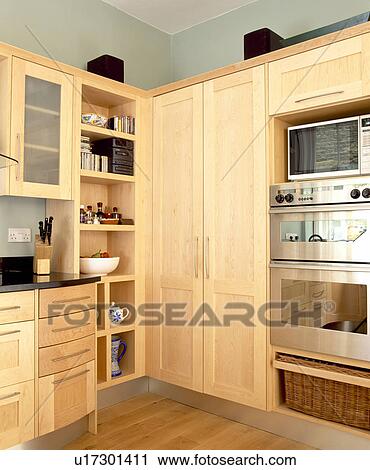 Stock Image - Pale wood units in modern kitchen with doors closed on larder cupboard. Fotosearch