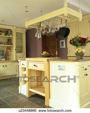 Pan rack above cream island unit in country kitchen View Large Photo Image Stock Photograph - Pan rack above cream island unit in country kitchen. Fotosearch