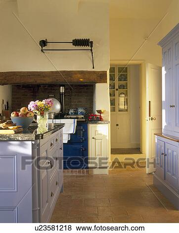 Stock Photo - Pastel blue fitted cupboards in traditional yellow kitchen with quarry tiled floor . Fotosearch