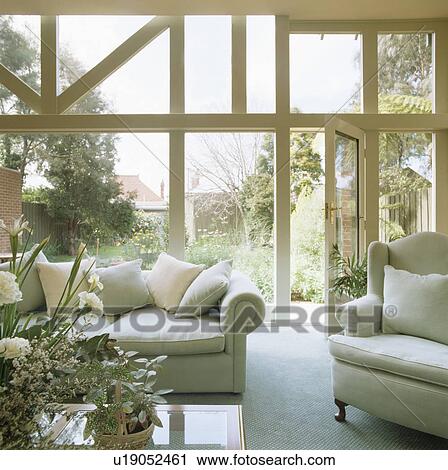 Stock Image - Pastel blue sofas in modern conservatory living room. Fotosearch