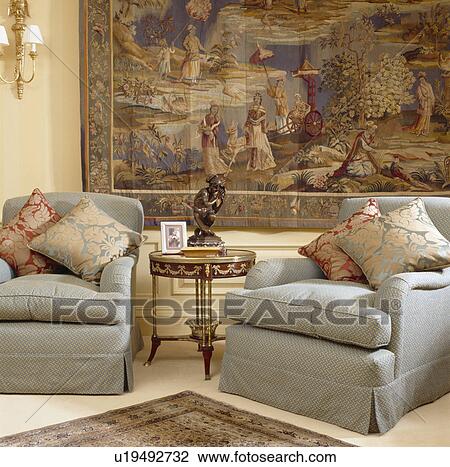 Patterned silk cushions on grey armchairs in front of large tapestry on wall of living room View Large Photo Image Stock Image - Patterned silk cushions on grey armchairs in front of large tapestry on wall of living room. Fotosearch