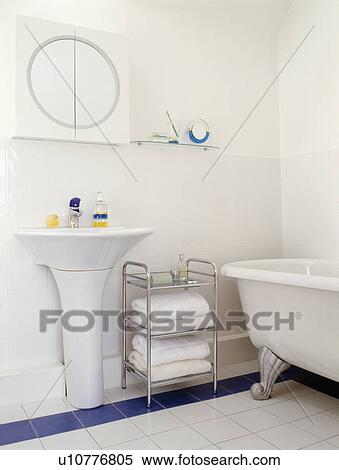 Stock Photography - Pedestal basin and stainless steel storage shelves in small modern white bathroom. Fotosearch