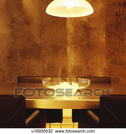 Pendant light above glass bowl on modern gilt table in dining room with textured walls View Large Photo Image Stock Image - Pendant light above glass bowl on modern gilt table in dining room with textured walls. Fotosearch