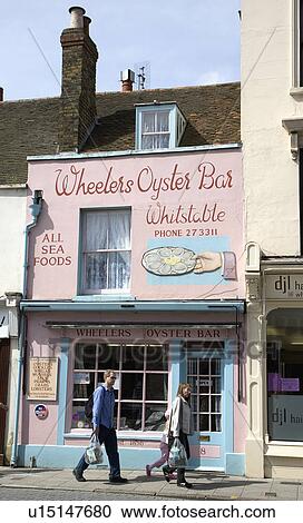 Stock Image - People walking past Wheeler's Oyster Bar in Whitstable, Kent. Fotosearch