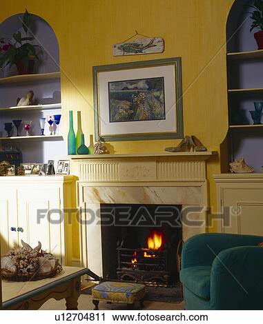 Stock Image - Picture above fireplace in yellow living room with blue alcoves. Fotosearch