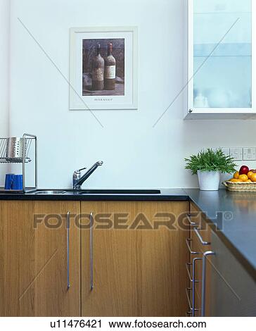 Stock Image - Picture above sink in fitted wood unit in modern kitchen. Fotosearch