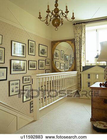 Stock Image - Pictures on wall above staircase on landing with cream carpet. Fotosearch