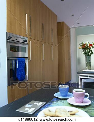 Stock Image - Pink and blue cups beside electric socket on worktop in modern kitchen. Fotosearch