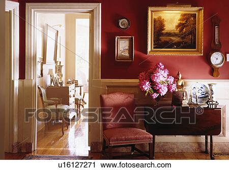 Pink chair beside antique table in red and cream traditional hall View Large Photo Image Stock Image - Pink chair beside antique table in red and cream traditional hall. Fotosearch
