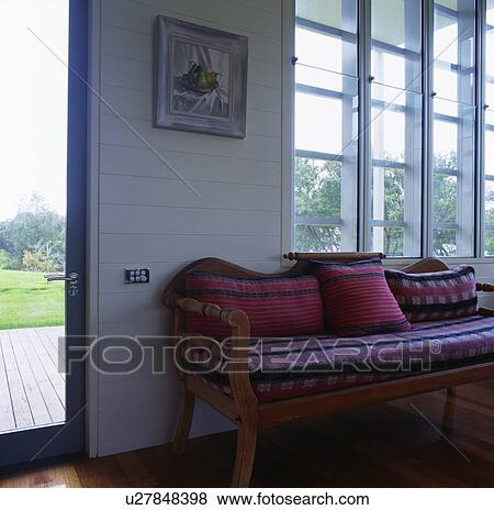 Pink cushions and checked upholstered cushion on wooden settle in modern hall View Large Photo Image Stock Photo - Pink cushions and checked upholstered cushion on wooden settle in modern hall. Fotosearch