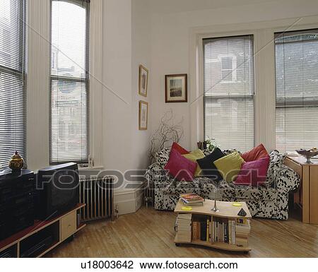 Stock Image - Pink cushions on animal-print sofa in modern white living room. Fotosearch
