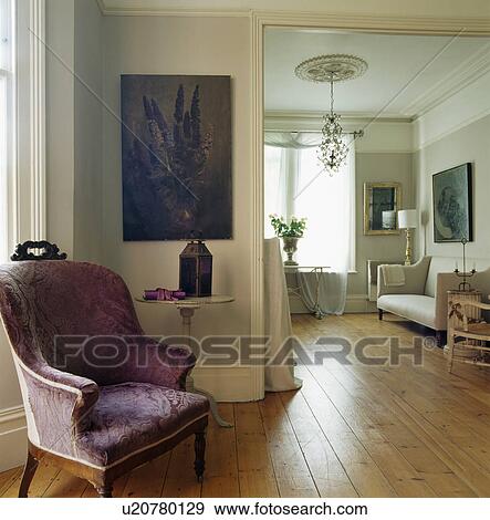 Stock Photo - Purple patterned armchair below picture beside double doorway in elegant living room with wooden flooring. Fotosearch