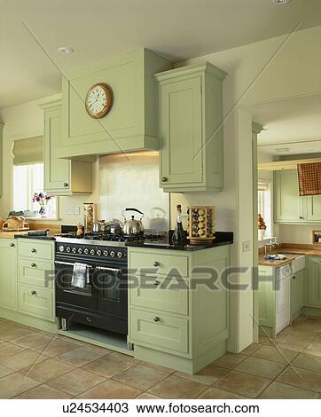 Stock Image - Range oven in traditional country kitchen pastel green fitted cupboards. Fotosearch