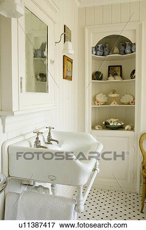 Reclaimed white basin in cream bathroom with seashells on alcove shelves View Large Photo Image Stock Photo - Reclaimed white basin in cream bathroom with seashells on alcove shelves. Fotosearch