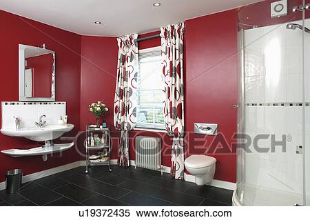 Stock Photography - Red patterned curtains in red bathroom with glass shower cabinet and black flooring. Fotosearch