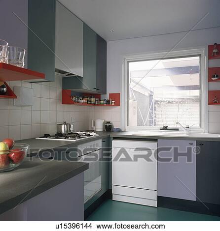 Picture - Red shelves in modern kitchen with blue fitted units. Fotosearch