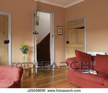 Red sofa and wooden flooring in economy-style living room with view of stairs through open door View Large Photo Image Stock Photo - Red sofa and wooden flooring in economy-style living room with view of stairs through open door. Fotosearch