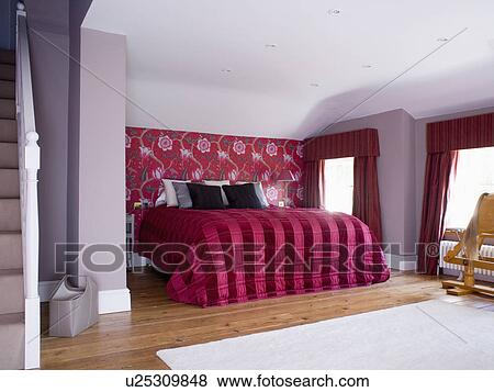 Stock Photo - Red+black striped silk quilt on bed in mauve bedroom with red floral patterned wallpaper. Fotosearch