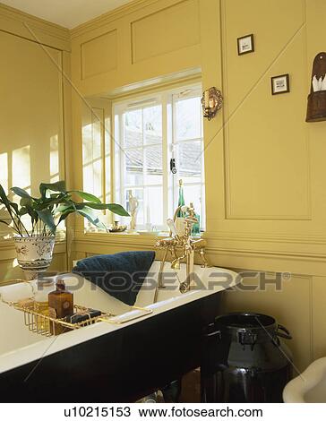 Roll-top bath with brass bath-rack in panelled yellow bathroom View Large Photo Image Stock Image - Roll-top bath with brass bath-rack in panelled yellow bathroom. Fotosearch