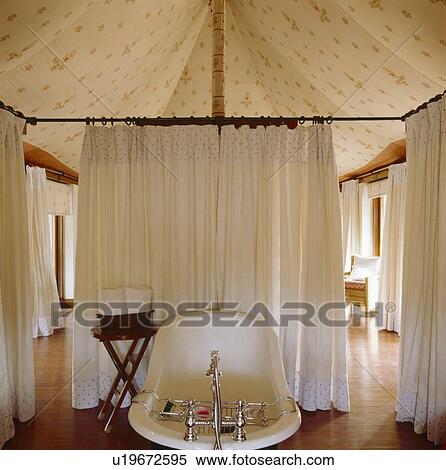 Rolltop bath and white linen curtains in bathroom in Rajastani tent with wooden flooring View Large Photo Image Stock Photography - Rolltop bath and white linen curtains in bathroom in Rajastani tent with wooden flooring. Fotosearch