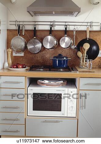 Saucepans on rack above fitted unit with hob and microwave oven View Large Photo Image Stock Photo - Saucepans on rack above fitted unit with hob and microwave oven. Fotosearch