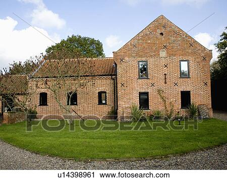 Stock Image - Semi-circular lawn in front of red brick converted barn. Fotosearch