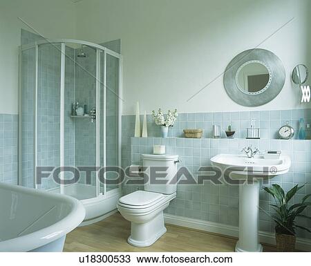 Stock Image - Shower cabinet in corner of bathroom with pastel blue wall tiles. Fotosearch