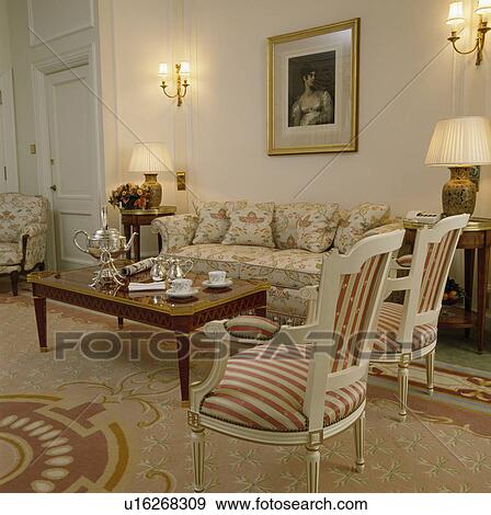 Stock Photo - Silver samovar and teaset on table in townhouse drawing room with lighted wall lights. Fotosearch