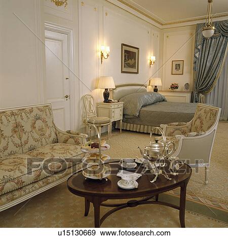 Stock Photo - Silver teaset with samovar on table in large townhouse bedroom with 17th century-style sofa and armchair. Fotosearch