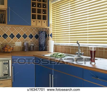 Slatted blind on window above sink in kitchen with blue fitted units View Large Photo Image Stock Image - Slatted blind on window above sink in kitchen with blue fitted units. Fotosearch