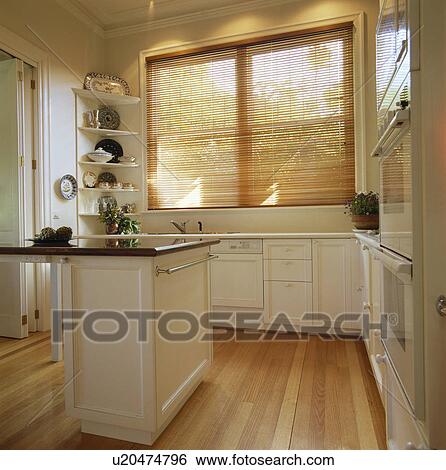 Stock Photograph - Slatted wooden blind and wooden flooring in modern white kitchen. Fotosearch