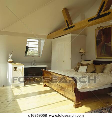 Stock Photo - Sleigh bed in loft bedroom with rolltop bath. Fotosearch