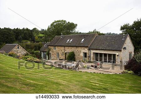 Sloping lawn down to traditional stone barn conversion with gravel terrace View Large Photo Image Stock Image - Sloping lawn down to traditional stone barn conversion with gravel terrace. Fotosearch