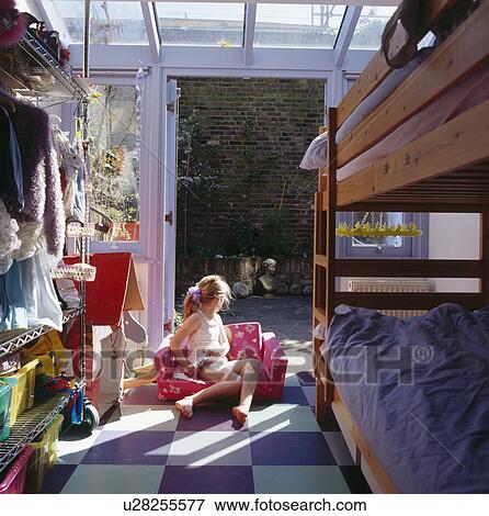 Stock Photo - Small girl sitting on chair in doorway of child's modern bedroom with bunkbeds. Fotosearch