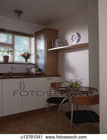 Stock Image - Small table with chairs in modern white kitchen. Fotosearch