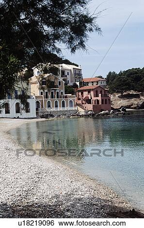 Stock Photograph - Small villas and stony beach at Assos on the island of Kefalonia in Greece&#10;. Fotosearch