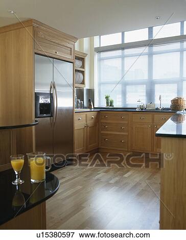 Stock Photo - Stainless steel American-style refrigerator in modern kitchen with wooden flooring. Fotosearch
