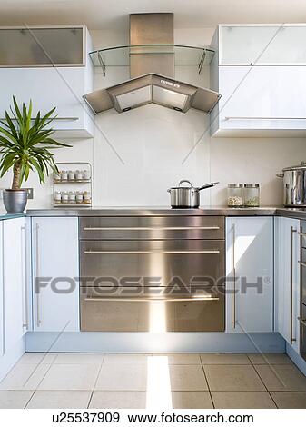 Stainless-steel and glass extractor above stainless-steel range oven in modern white kitchen with pastel blue units View Large Photo Image Stock Photo - Stainless-steel and glass extractor above stainless-steel range oven in modern white kitchen with pastel blue units. Fotosearch